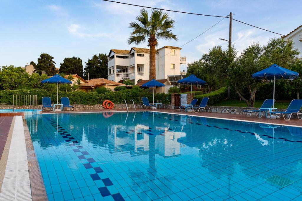 una gran piscina con sillas y sombrillas azules en Ionio Holidays Katerina Apartments, en Vasilikos