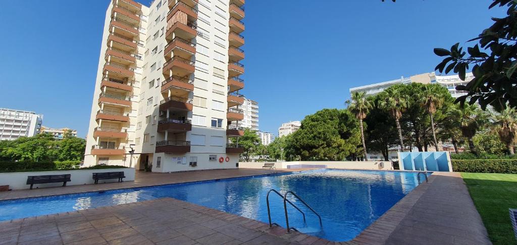 a swimming pool in front of a tall building at Apartamento Geminis I in Playa de Gandia