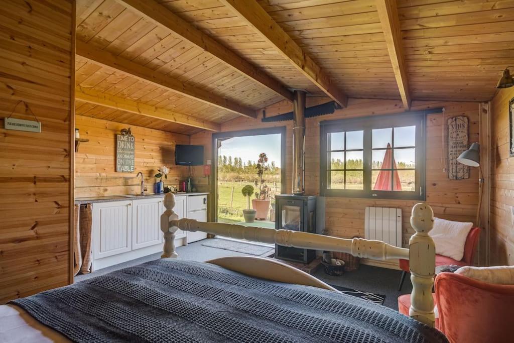 a bedroom in a log cabin with a bed and a kitchen at Secret & Secluded Sedlescombe in Battle