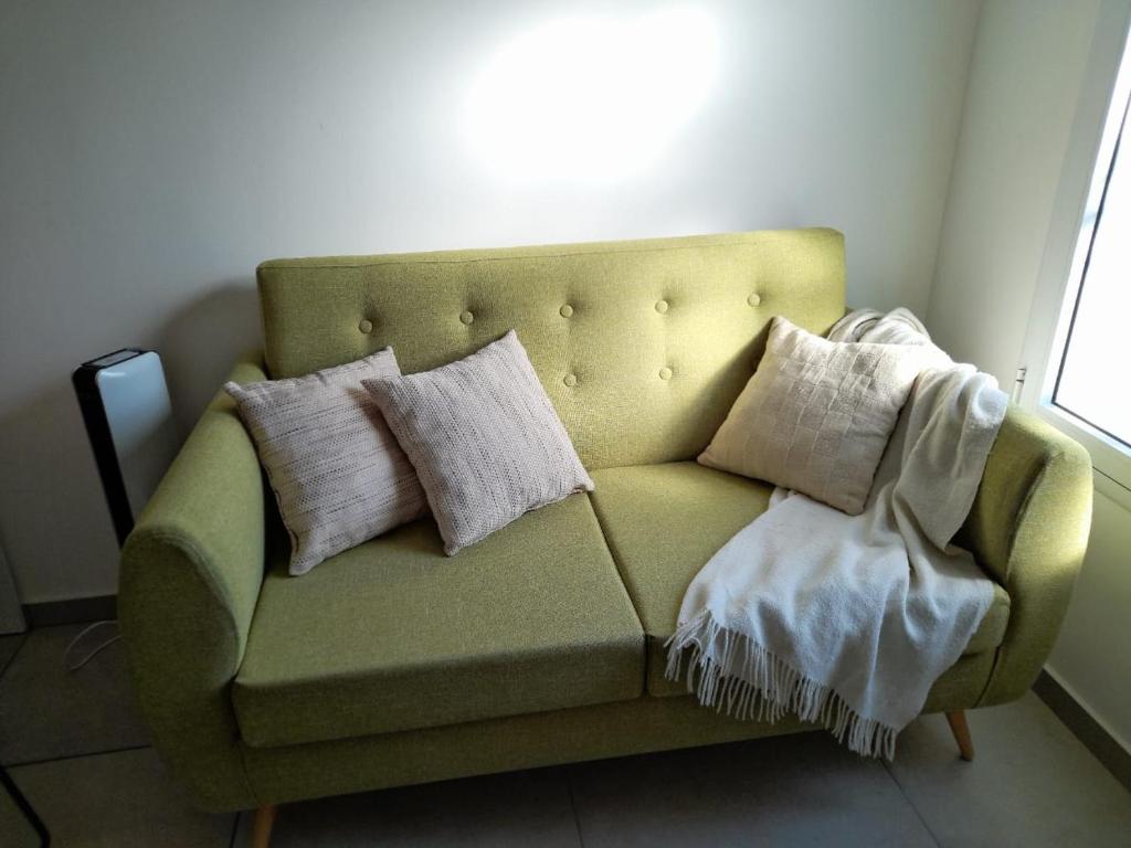 ein grünes Sofa mit Kissen darauf im Zimmer in der Unterkunft Departamento moderno y luminoso, en planta baja, con patio y excelente ubicación in Rafaela