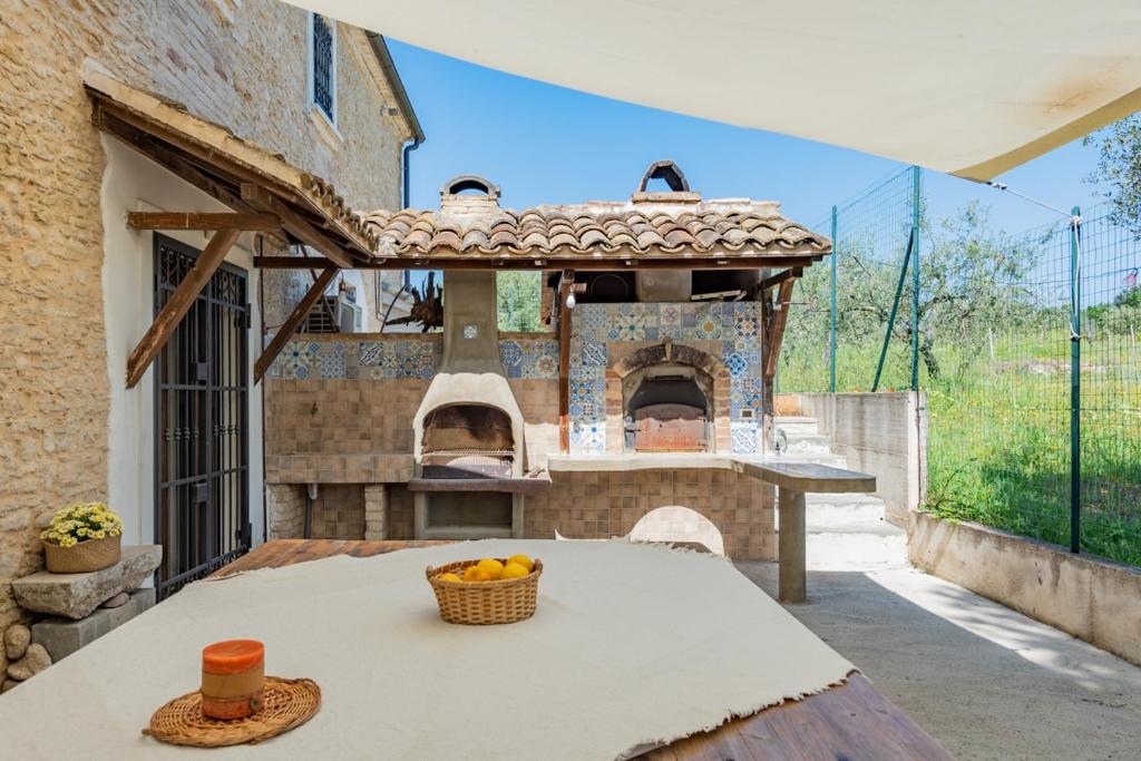 una cucina all'aperto con tavolo e forno per pizza di Il fico nel Pozzo - YourPlace Abruzzo a Fossacesia