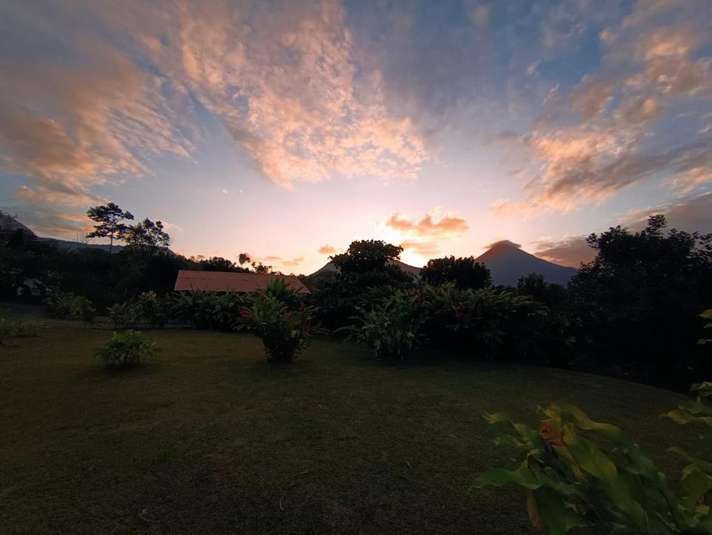 una puesta de sol sobre un patio con una casa y árboles en Cabaña Rural el Mirador, en Fortuna