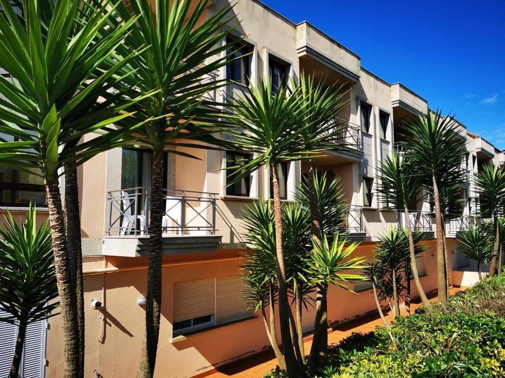 un edificio con palmeras delante en Duerming Montalvo Playa Hotel, en Montalvo