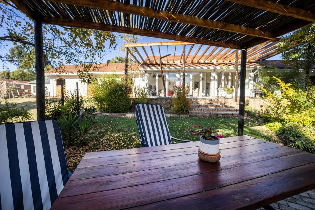 a wooden table and chairs under a pergola at Windsong Living - Eagle Owl in Krugersdorp