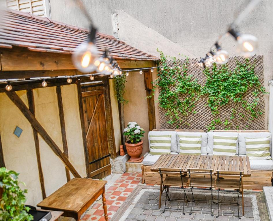 um pátio com uma mesa de madeira e cadeiras brancas em Maison Simart em Troyes