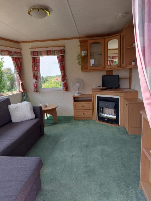 a living room with a couch and a tv in a caravan at Domek holenderski Sosnowa in Wilkasy