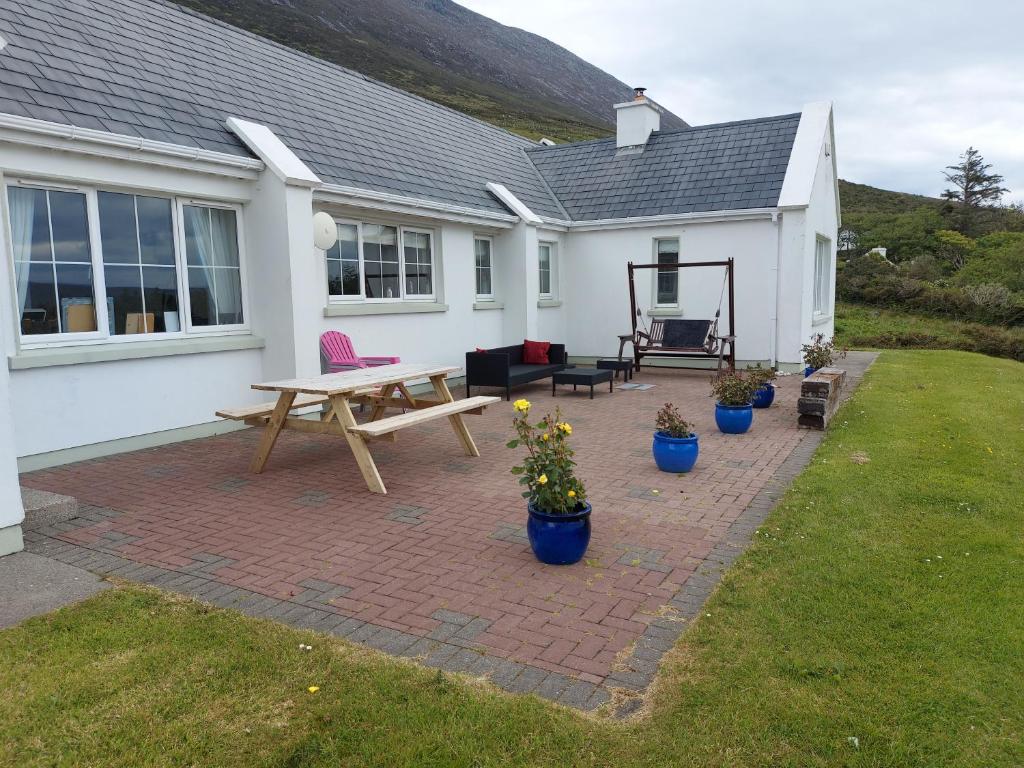 un patio con mesa de picnic y macetas frente a una casa en Minaun Cliff View en Achill