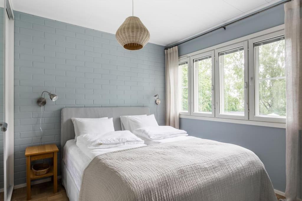 1 dormitorio con 1 cama con sábanas blancas y ventanas en Upea remontoitu huoneisto Naantalin sydämessä, en Naantali