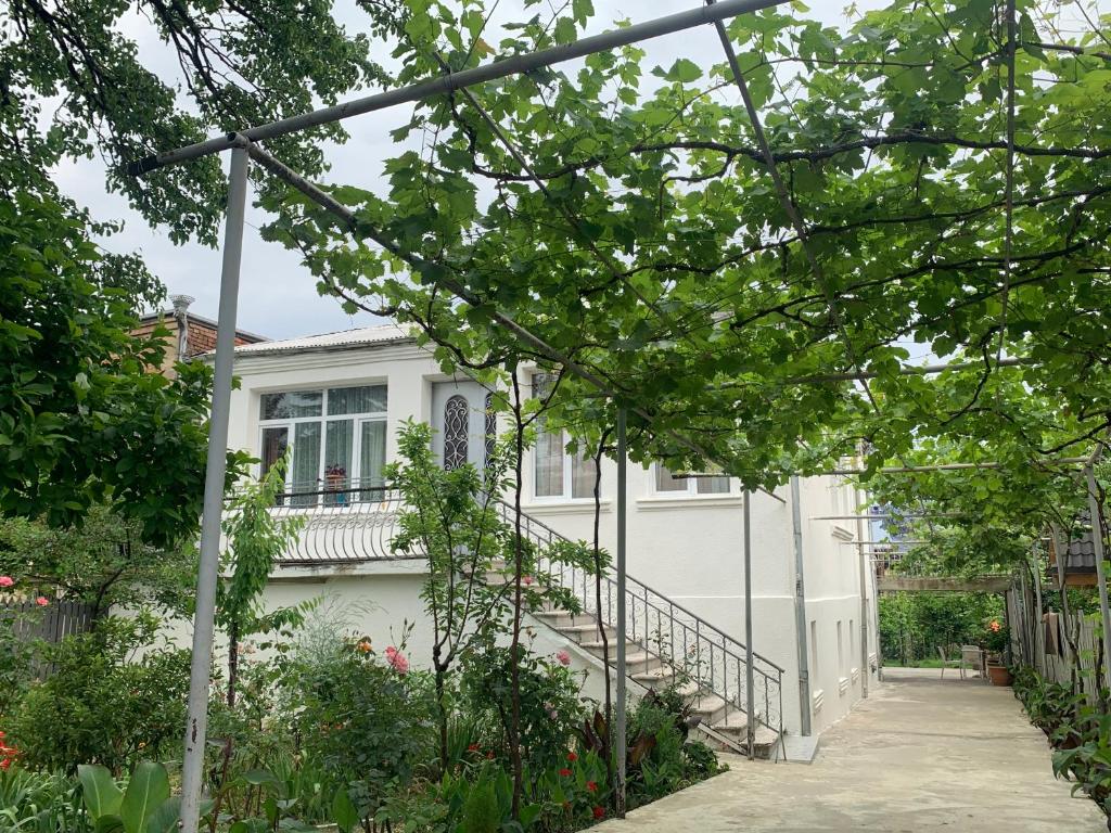 a white house with a staircase in front of it at Hostel FORREST in Kutaisi