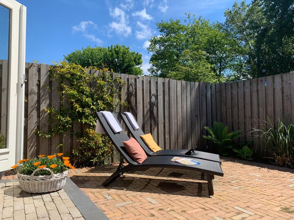 einen Stuhl auf einer Terrasse neben einem Zaun in der Unterkunft B&B Beach House Texel in De Koog