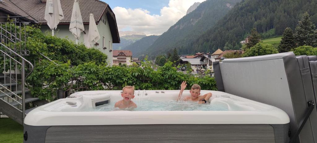a man and a child in a hot tub at Hotel Garni Snaltnerhof in Ortisei