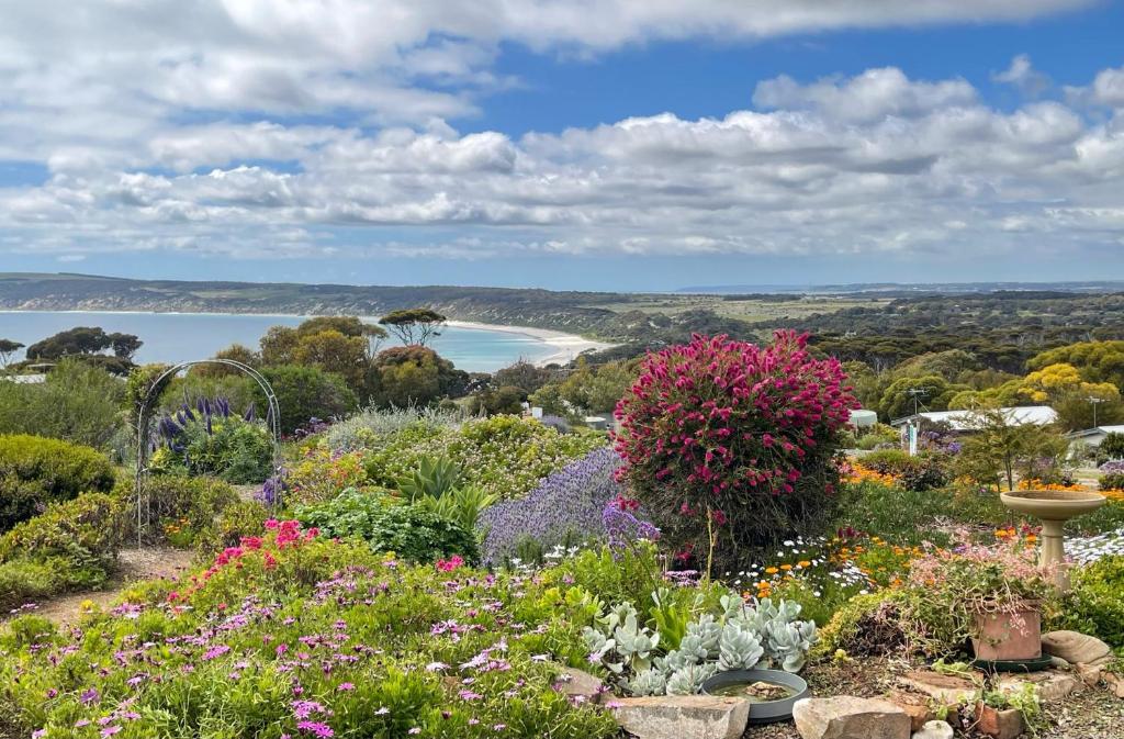 a garden with flowers and a beach in the background at Emu Bay Holiday Homes in Emu Bay