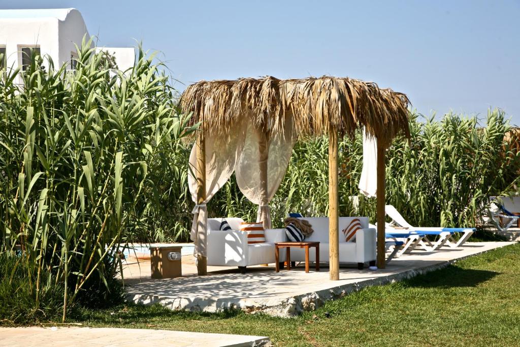 a patio with a straw umbrella and chairs and tables at Thalassines Villas in Ayia Napa
