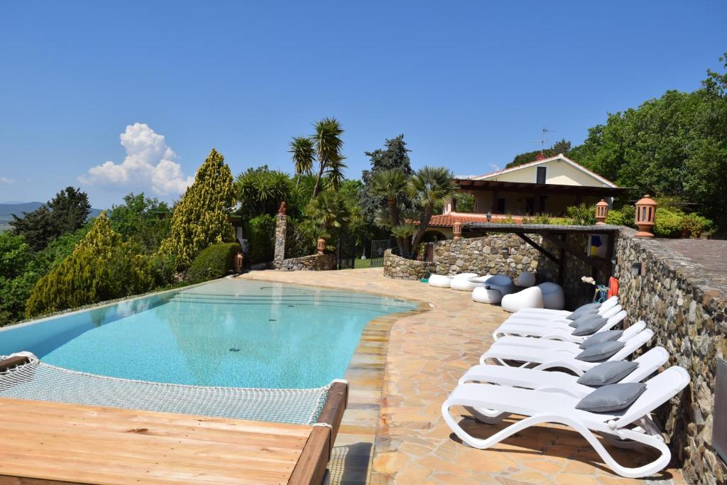 una fila di sedie a sdraio accanto alla piscina di Villa Le Agavi & Spa a Scarlino