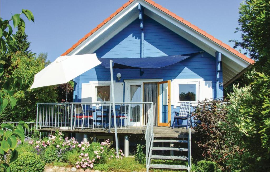 ein blaues Haus mit einem Sonnenschirm, Stühlen und Tischen in der Unterkunft Ferienhaus Aaskuhle W in Schwarz