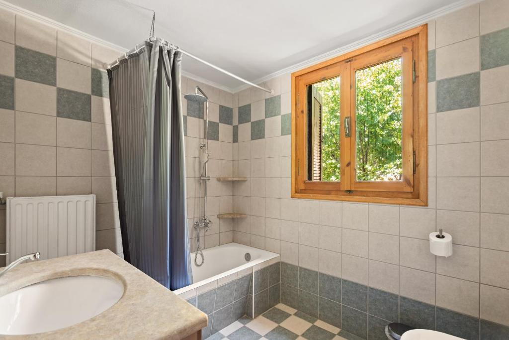 a bathroom with a sink and a tub and a window at Dimitra's Studios in Stoupa