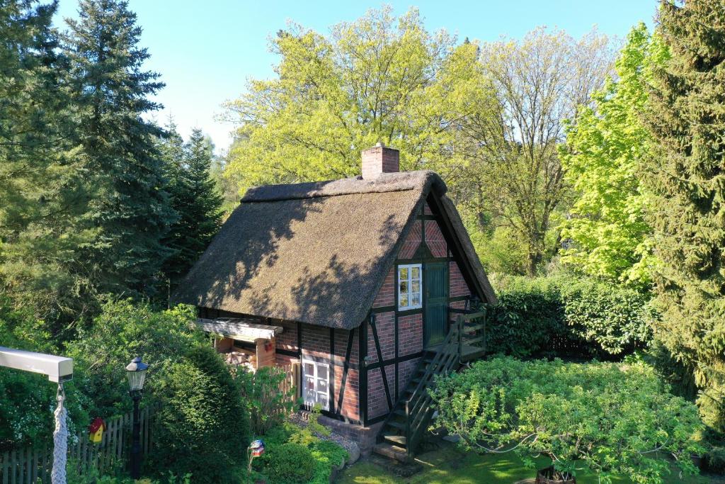 een oud huis met een rieten dak in een tuin bij Ferienhaus unter Reet im Heidedorf Sankt Dionys bei Lüneburg in Sankt Dionys