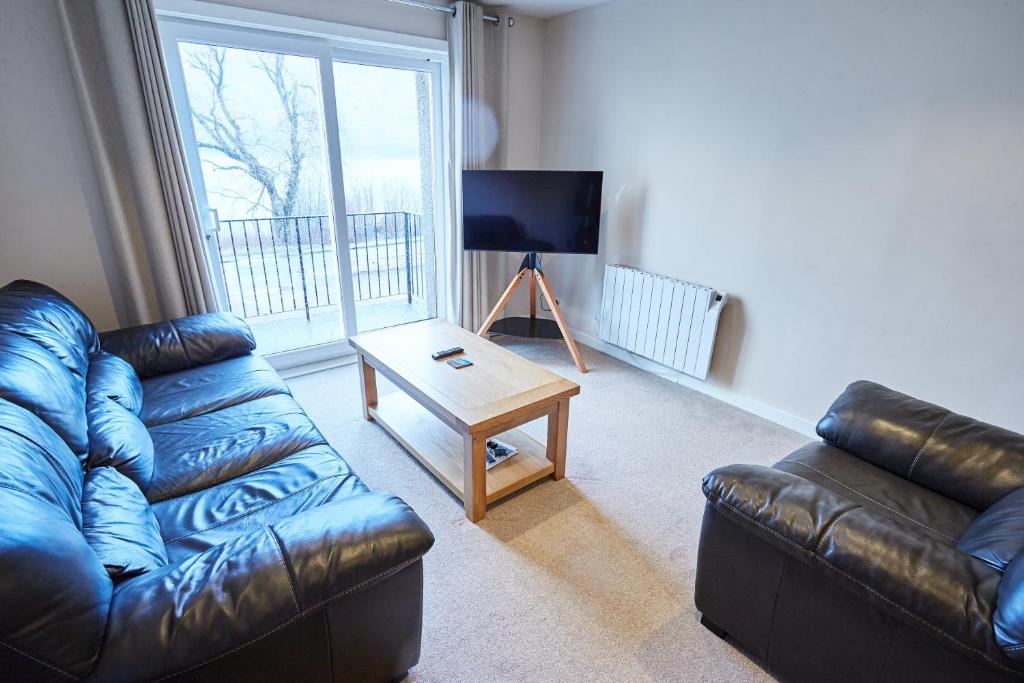 a living room with a leather couch and a table at Etive, Beautiful Lochside Apartment with balcony in Fort William