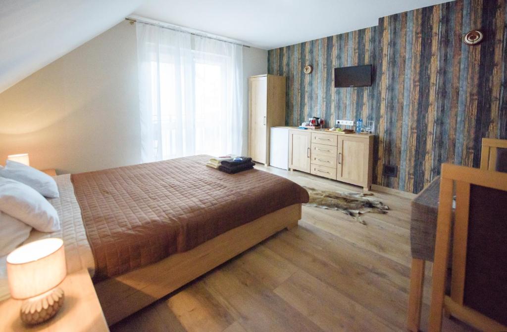 a bedroom with a bed and a dresser and a television at Willa Mysliwska in Krynica Morska