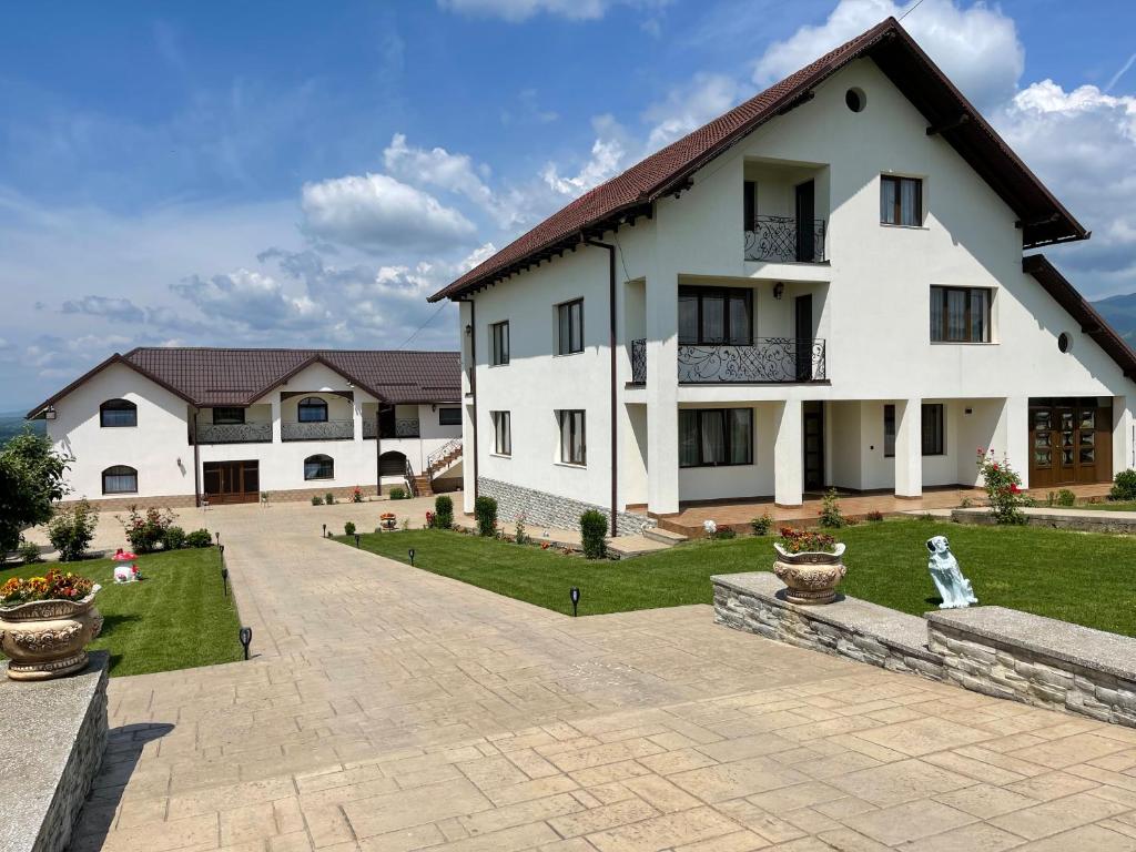 a large white house with a courtyard at Pensiunea Novis in Novaci