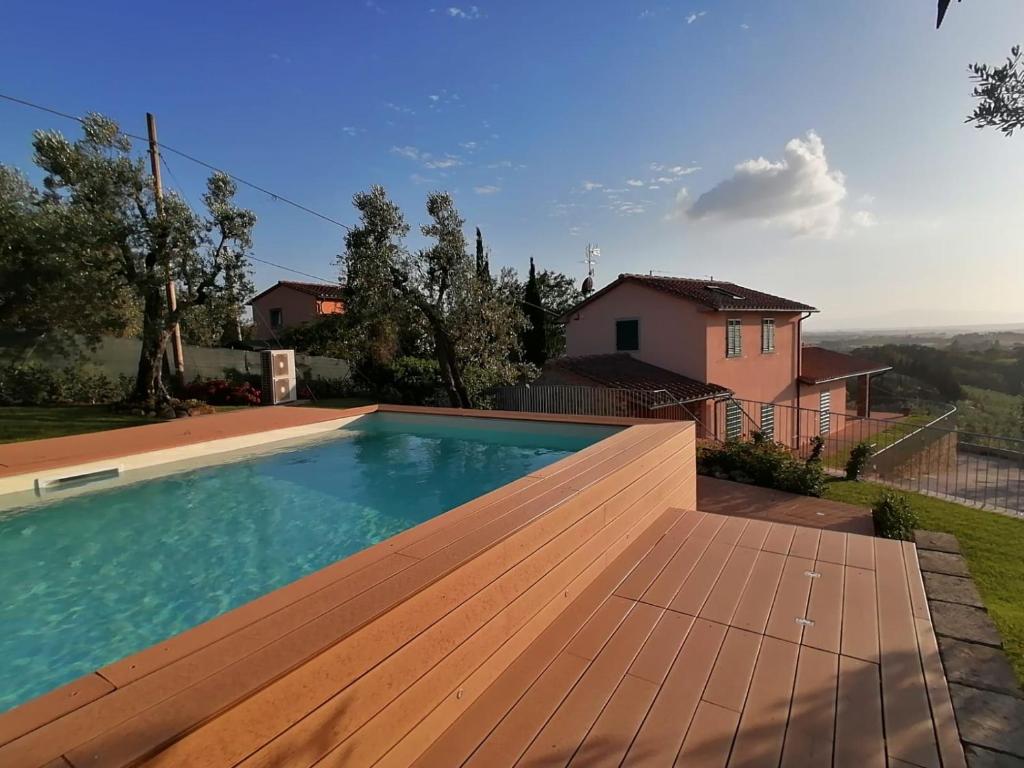 een zwembad met een houten terras en een huis bij A Casa di Patrizia in Vinci