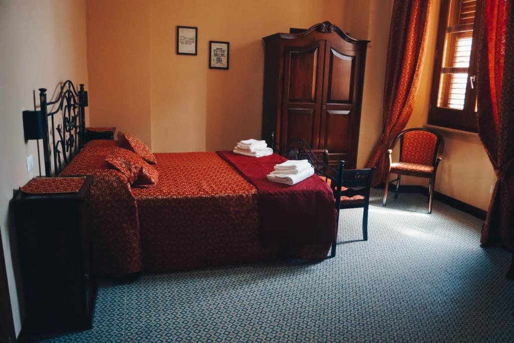 a bedroom with a bed and a chair and a window at La Stazione in Piazza Armerina