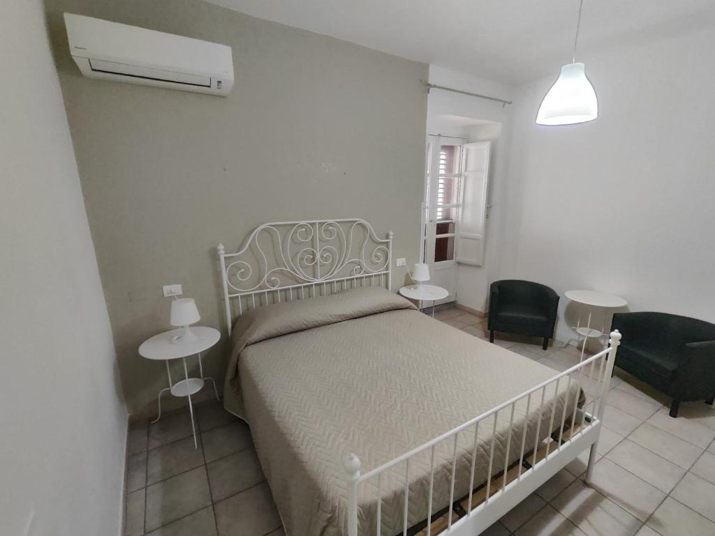 a white bedroom with a bed and a chair at B&B Del Carmine in Noto