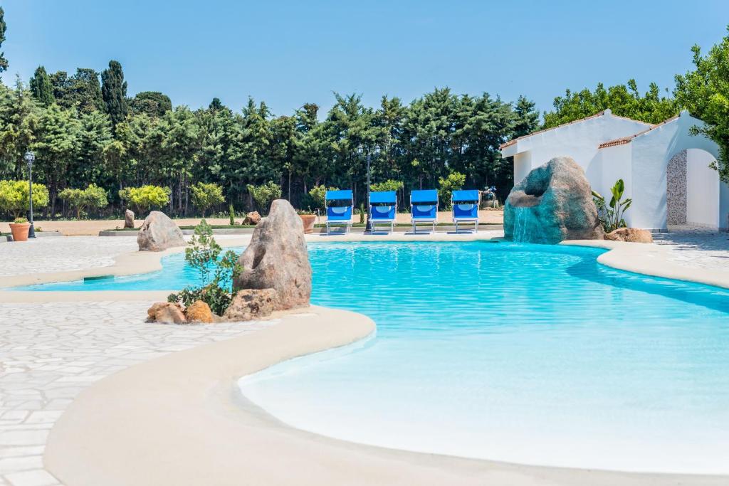 a pool with chairs and rocks in a resort at Sisula Country Hotel & SPA in Orosei