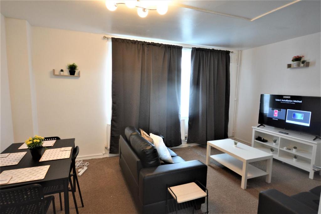 a living room with a black couch and a tv at Beautiful Two Bedroom Flat in Brixton London in London