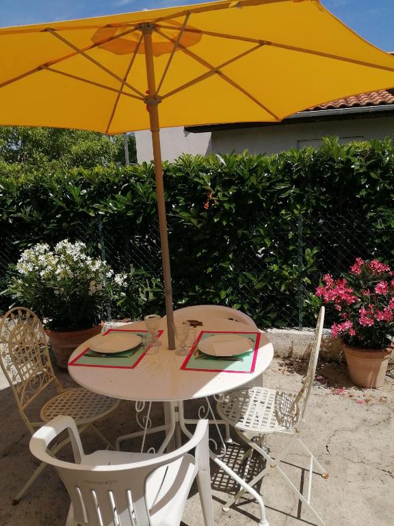 un parapluie jaune assis sur une table avec des chaises dans l'établissement Villa l'bontemps, à Saint-Georges-de-Didonne