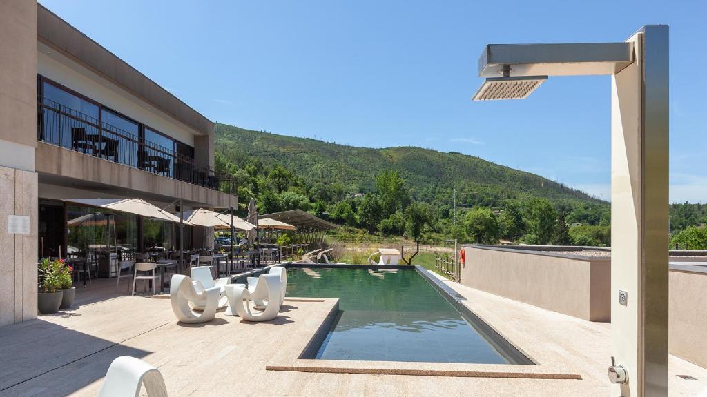 a resort with a swimming pool with a mountain in the background at Aqua Village, Health Resort in Oliveira do Hospital