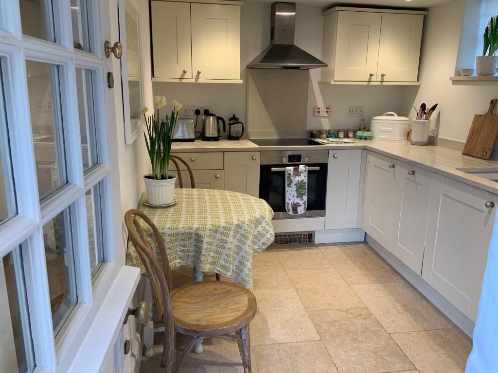 uma cozinha com uma mesa e uma mesa e cadeiras em Masons Cottage, an Idyllic retreat in an area of outstanding beauty, close to Blenheim Palace, Oxford & The Cotswolds em Stonesfield