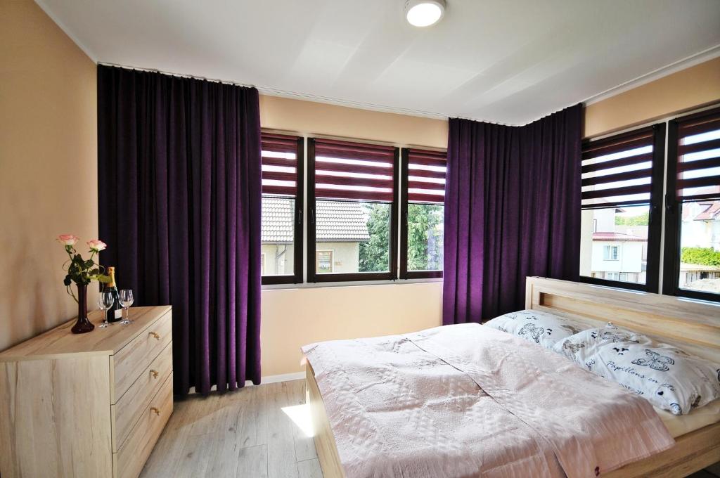 a bedroom with a large bed with purple curtains at BALTIC VIBES - pokoje gościnne in Kołobrzeg