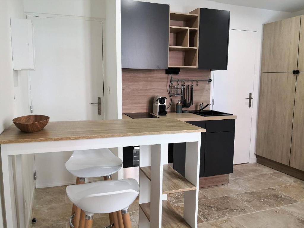 une cuisine avec une table et deux tabourets blancs dans l'établissement Orange Théâtre Studio, à Orange