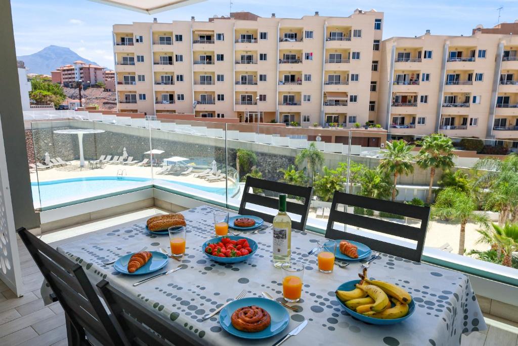 a table with food and fruit on a balcony with a pool at Ocean Garden Beautiful FREE WIFI in Playa Paraiso