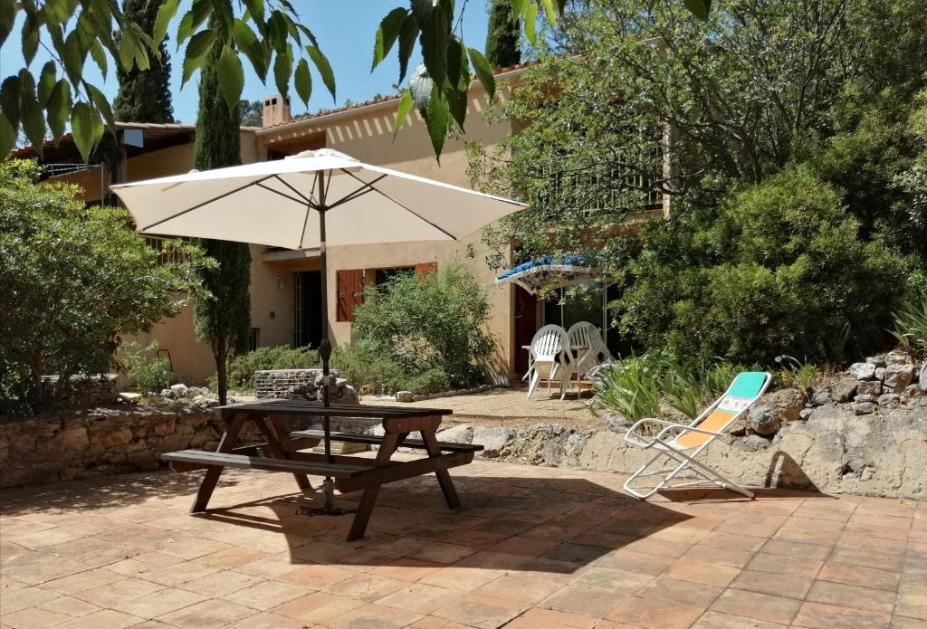 - une table de pique-nique avec un parasol et une chaise dans l'établissement T2 36 m2, RdC de villa, clim, gd jardin clos, animx ok, quartier Mt Faron très calme, wifi, parking, à Toulon