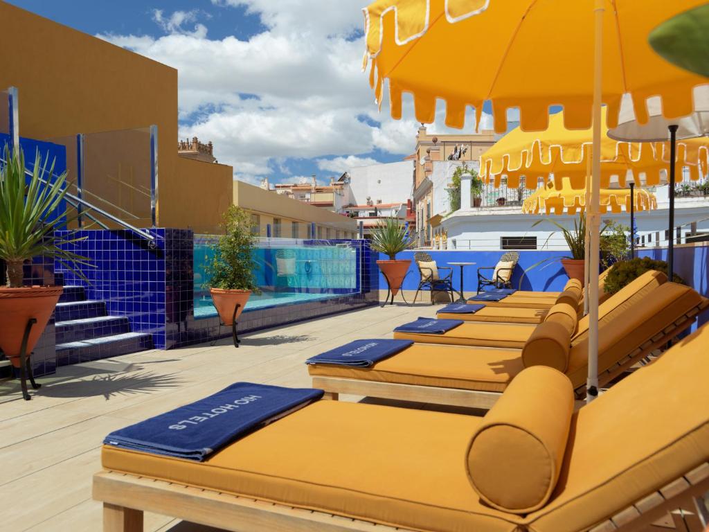 a row of lounge chairs sitting on top of a beach at H10 Corregidor Boutique Hotel in Seville
