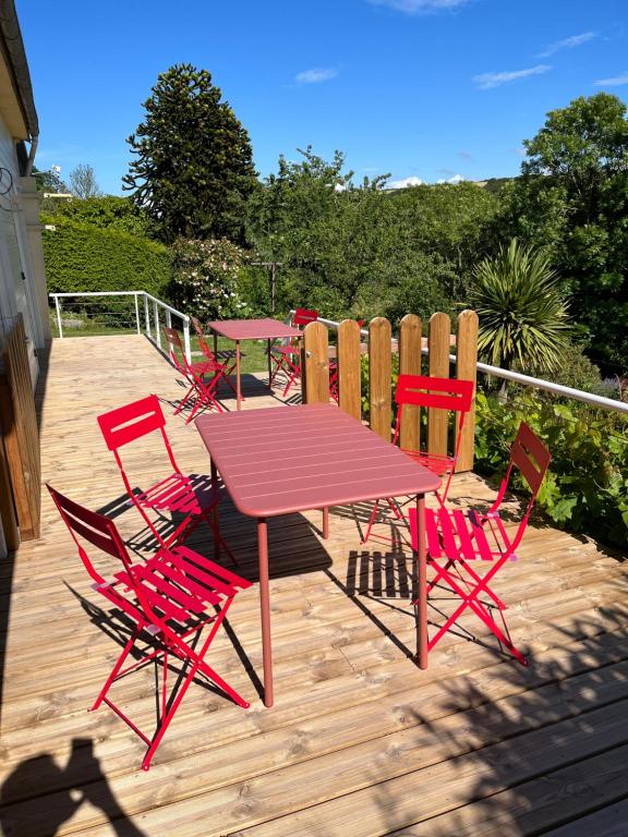 una terraza de madera con mesa y sillas rojas en l'Amont et l'Aval, en Étretat