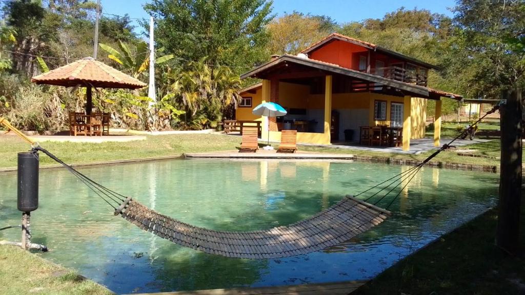 a hammock around a pool in front of a house at Sitio Espelho Dagua - Brotas SP in Brotas