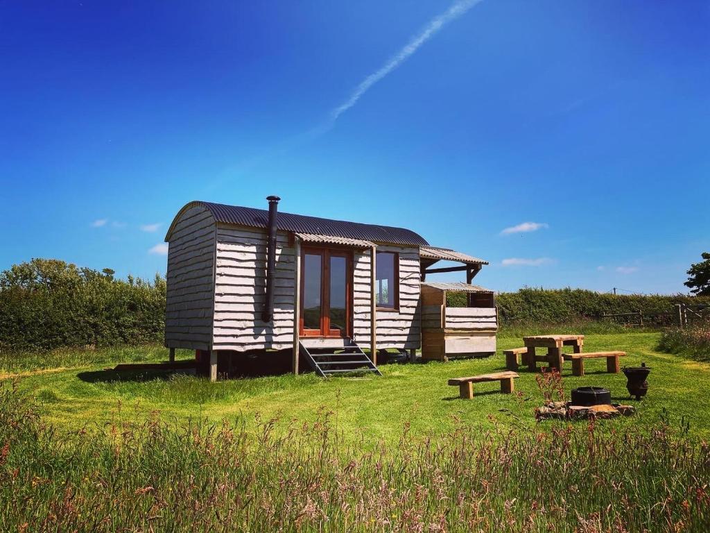 a tiny house sitting in a grassy field at Shepherds Hut in a private meadow with sea views in Hartland