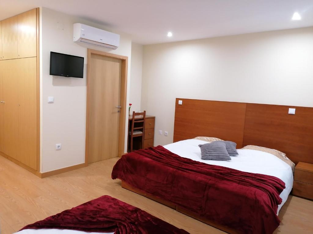 a bedroom with a bed and a flat screen tv at Colina do Ave Alojamento Local in Ribeirão