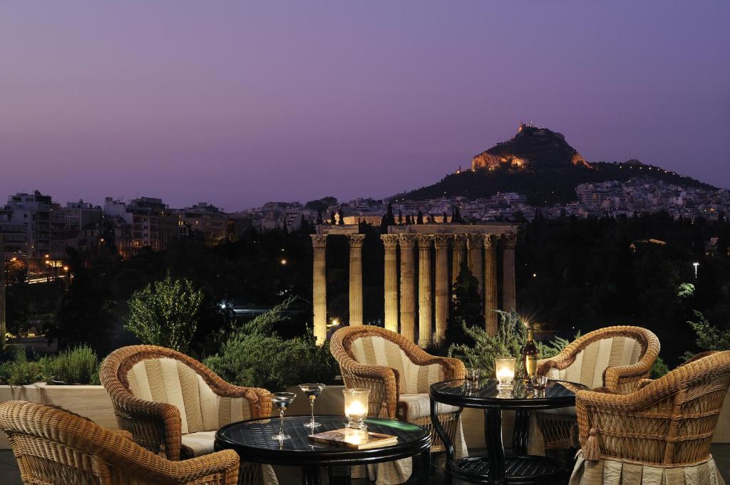 eine Terrasse mit Tischen und Stühlen und Stadtblick in der Unterkunft Royal Olympic Hotel in Athen