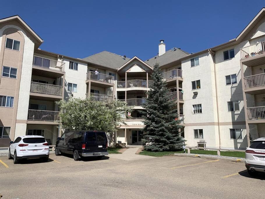 a large apartment building with cars parked in a parking lot at Chris Cozy Condo Commonwealth Edmonton in Edmonton