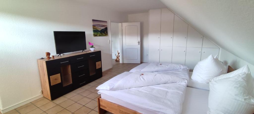 1 dormitorio con 2 camas y un tocador con TV en Diemeltal Lodge Ferienwohnung, en Marsberg