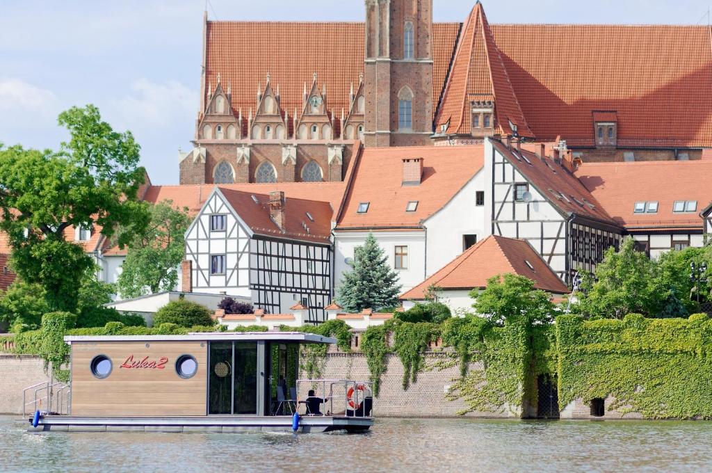 a boat on a river in front of a city at Apartament na wodzie - Riveraparts - Marina Oława in Oława