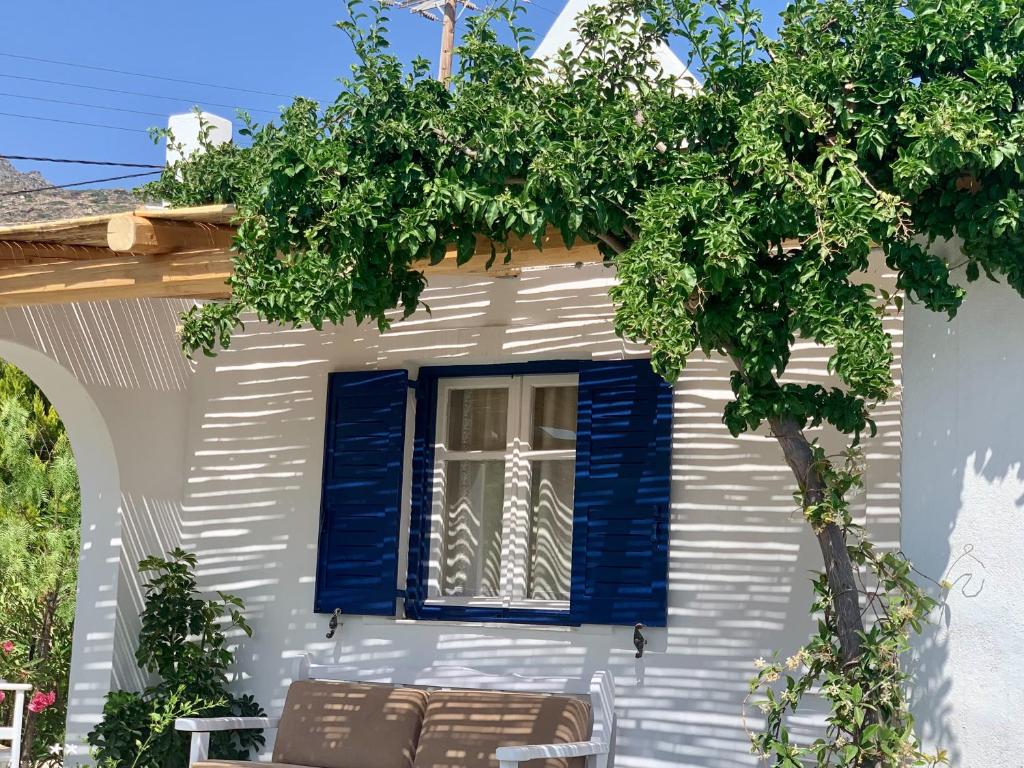 a house with blue shutters and a tree at Spiti Apartment in Mylopotas