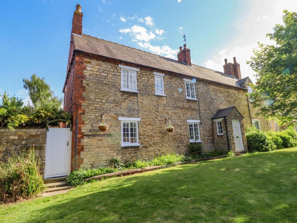 an old brick house with a lawn in front of it at Old Rectory Cottage in Lincoln