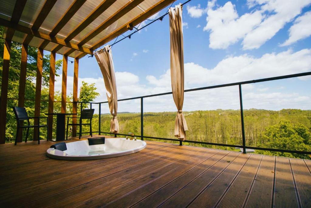 a deck with a hot tub and a view of the woods at In Heaven in Zdów