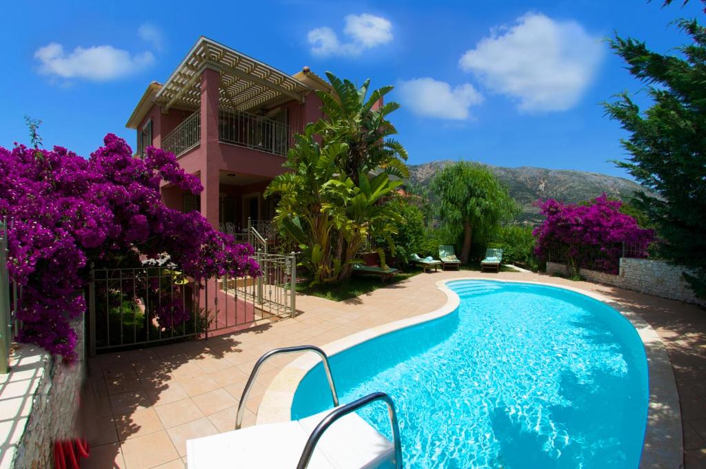 a villa with a swimming pool in front of a house at Stamoulis Villas in Ayia Evfimia