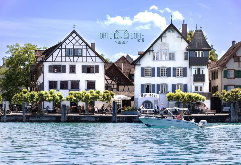 a boat in the water in front of buildings at Hotel Porto Sofie Gottlieben in Gottlieben